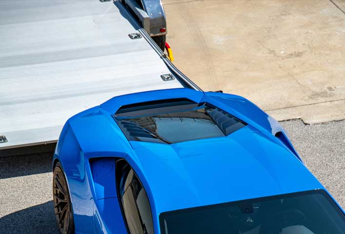 McCollisters - A blue auto is partially shown from above, positioned near a flatbed trailer on a concrete surface—a dynamic scene of modern transportation.