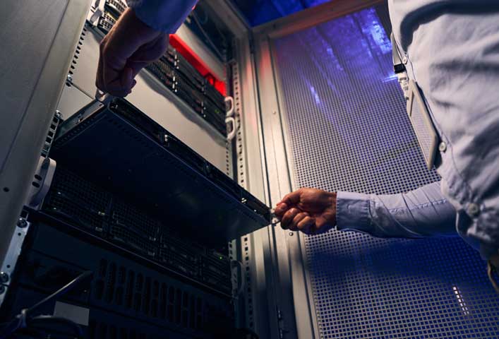 McCollisters Two people are handling the installation of a server in a data center rack. One slides the server in while the other steadies the tray, under cool and warm lighting—a critical task for industries like banking and retail.