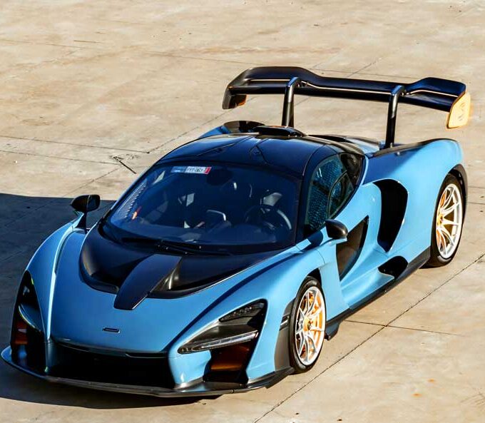 McCollisters A blue McLaren Senna sports car with a large rear wing is parked on a sunlit concrete surface, viewed from above—an ideal candidate for car shipping that emphasizes flexibility in auto transport solutions.